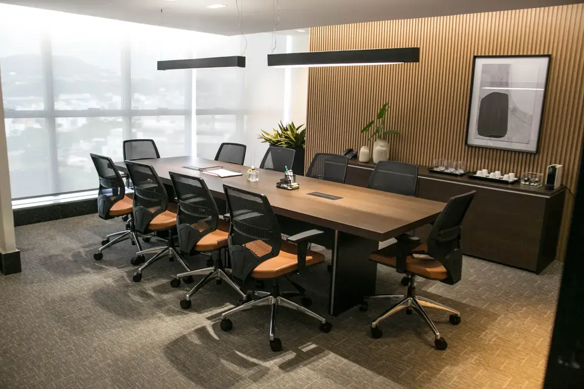 Sala de reunião com mesa, cadeiras de escritório e piso.